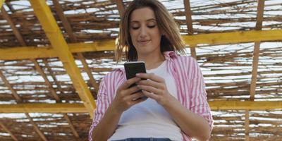 mujer smartphone enviando mensajes de texto por teléfono celular en la playa foto