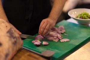 chef manos cortando la cebolla con cuchillo foto