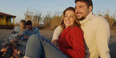 Loving Young Couple Sitting On The Beach beside Campfire drinking beer photo