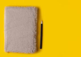 notebook,pen, on yellow background. top view photo