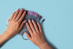 Woman holds in hands collection of color nail polish samples photo