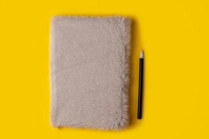 notebook,pen, on yellow background. top view photo