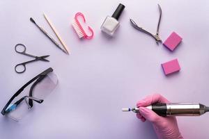 A manicurist in gloves holds a nail drill. photo