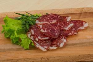 Sliced salami on wooden board and wooden background photo