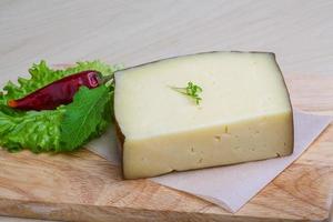 Hard cheese on wooden board and wooden background photo