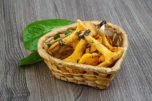 Chanterelle in a basket on wooden background photo