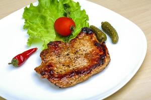 cerdo asado en el plato y fondo de madera foto