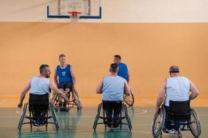 veteranos de guerra discapacitados de raza mixta que se oponen a equipos de baloncesto en sillas de ruedas fotografiados en acción mientras juegan un partido importante en una sala moderna. foto