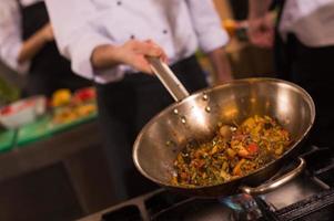 chef flipping vegetables in wok photo