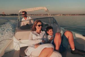 una pareja mayor con ropa informal con su hijo disfruta mientras viaja en un bote en el mar al atardecer. el concepto de una familia feliz. enfoque selectivo foto