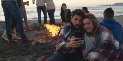 Couple enjoying bonfire with friends on beach photo