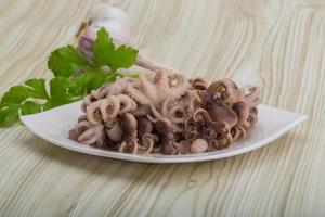 Boiled octopus on the plate and wooden background photo