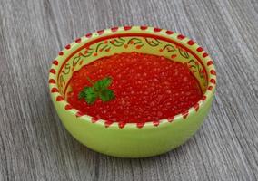 Red caviar in a bowl on wooden background photo