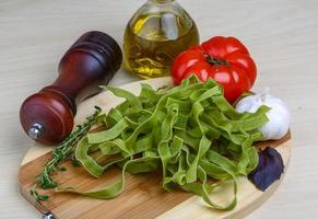 Raw tagliatelle on wooden board and wooden background photo