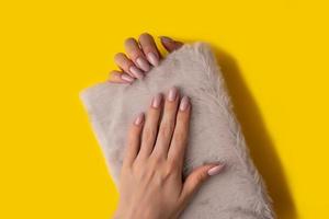 Female hands with a beautiful manicure on a yellow background,top view photo