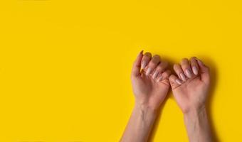 Female hands with a beautiful manicure on a yellow background,top view photo