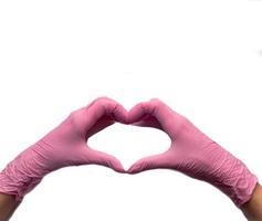 Women's hands in pink gloves hold heart-shaped hands on white background photo