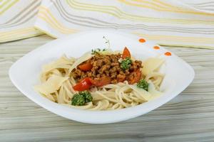 pasta boloñesa en el plato y fondo de madera foto