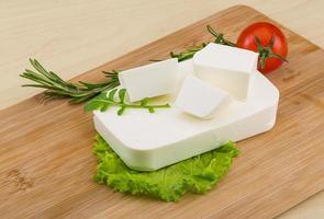 Feta cheese on wooden board and wooden background photo