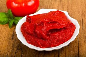 Tomato paste on the plate and wooden background photo