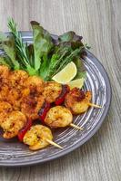 Prawn skewer on the plate and wooden background photo