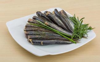 Salted anchovy on the plate and wooden background photo