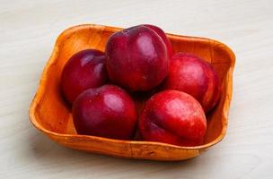 Nectarines in a bowl on wooden background photo