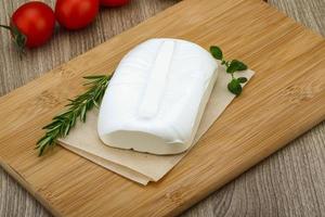 Feta cheese on wooden board and wooden background photo