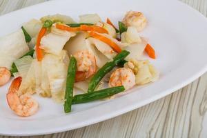 Shrimp salad on the plate and wooden background photo