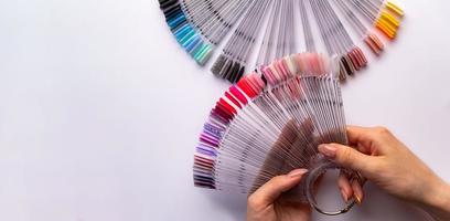 Woman holds in hands collection of color nail polish samples photo