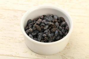 Dry barberry in a bowl on wooden background photo