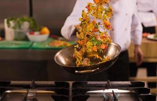 chef flipping vegetables in wok photo