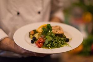 Chef hands holding dish of fried Salmon fish fillet photo