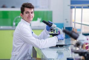 estudiante científico mirando a través de un microscopio foto