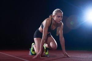 woman  sprinter leaving starting blocks photo