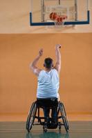 un inválido de guerra en silla de ruedas entrena con una pelota en un club de baloncesto en entrenamiento con equipo deportivo profesional para discapacitados. el concepto de deporte para personas con discapacidad foto