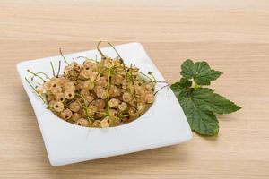 White currant in a bowl on wooden background photo