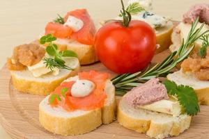 Assorted tapas on wooden board and wooden background photo