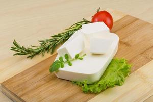 Feta cheese on wooden board and wooden background photo