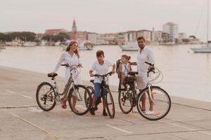 la familia feliz disfruta de una hermosa mañana junto al mar andando en bicicleta juntos y pasando tiempo juntos. el concepto de una familia feliz foto