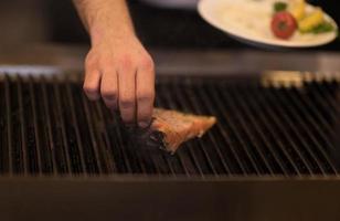 chef manos cocinando salmón a la parrilla foto