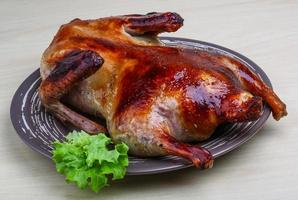 Roasted duck on the plate and wooden background photo