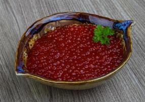 caviar rojo en un recipiente sobre fondo de madera foto