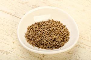 Cumin seeds in a bowl on wooden background photo