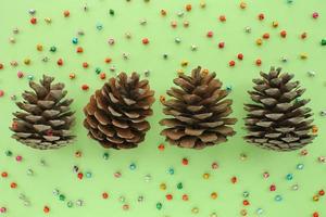 Pine fir cones of coniferous tree and jingle bells isolated on green background. Creative christmas holiday composition. Decoration for postcard. Top view, copy space, flat lay, close up photo