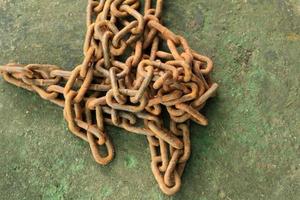 Rusty and dirty steel chains on cement floor in front of the house for locking valuable assets such as motorcycles and bicycles to prevent guerrilla theft. photo