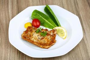 Pork schnitzel on the plate and wooden background photo