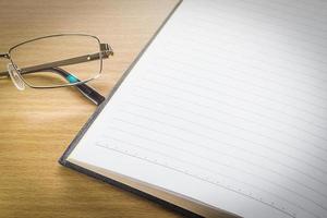 Eyeglasses and open note book with blank page photo