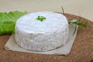 queso brie sobre tablero de madera y fondo de madera foto