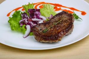 bistec en el plato y fondo de madera foto